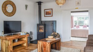Un saló agradable amb televisió, mobles de fusta, una llar de foc i vistes a l'habitació.