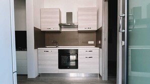A modern kitchen with light wood cabinets, a stainless steel range hood, and a built-in oven. - Viareggio House Renovated July 2024 (Viareggio)