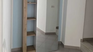 Habitación con armario empotrado frente a una pared azul claro, con varios estantes y un espejo.