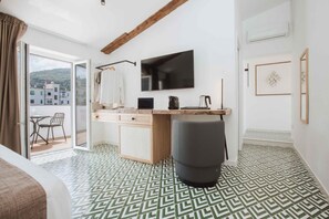 A modern hotel room with a bed, a desk, a TV, and a view of the city.