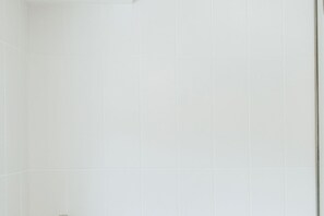 A bathroom with white tiled walls and floor.
