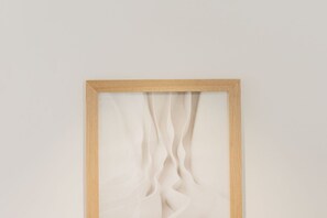 A framed artwork with a wooden frame and a white background.