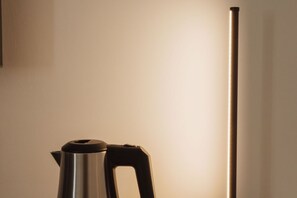 A stainless steel kettle with a black handle on a white surface.