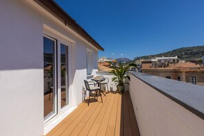A balcony with a wooden floor, a table with chairs, and a potted plant.