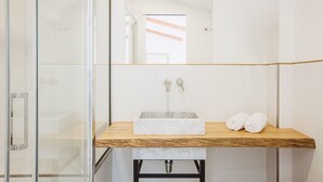 Een badkamer met een douchecabine van glas, een marmeren wastafel en een houten aanrecht.