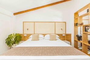 Una camera da letto ordinata con un letto grande, una testiera in legno, una pianta sul comodino e una libreria in legno.