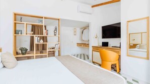 Een hotelkamer met een bed, een bureau met een computer, een stoel, een kledingkast en een televisie.