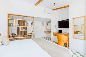Una camera d'albergo con un letto, una scrivania con un computer, una sedia, un armadio e una televisione.