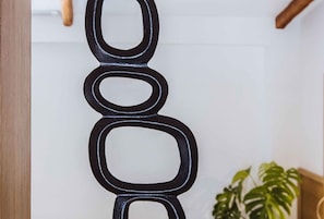 Eine schwarze, abstrakte Wanddekoration mit einem hölzernen Türrahmen und einer grünen Pflanze im Hintergrund.