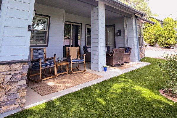 A house with a covered porch, stone foundation, and a well-maintained lawn.