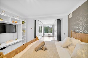 Ein modernes Schlafzimmer mit einem großen Bett, einem Fernseher, eingebauten Regalen und Blick auf einen Balkon.