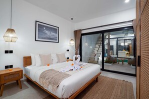 A modern hotel room with a large bed, a view of the outdoor area, and a staircase leading to an upper level. - Villa Flambard (Canggu)