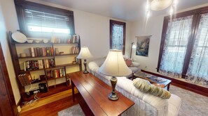 A cozy living room with a wooden coffee table, a sofa, and a bookshelf filled with books.