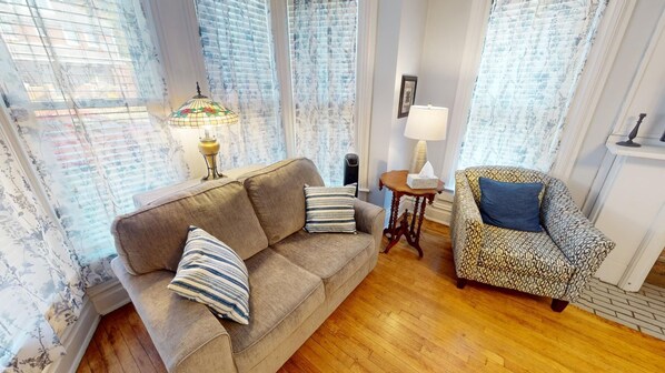 A living room with a sofa, patterned armchair, and a lamp.