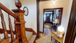 A wooden staircase with a handrail and a light fixture on a table in the hallway.