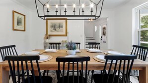 A dining room with a wooden table, black chairs, and a geometric chandelier. - Wildwood Retreat - Theater, Hot Tub and More! (Lake Geneva)