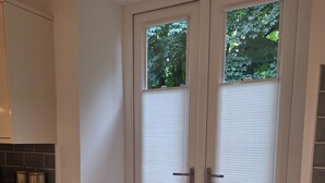 Eine Doppeltür mit satinierten Glasscheiben, eine schwarze Fußmatte und eine Holzauskład mit einer gefliesten Rückwand.