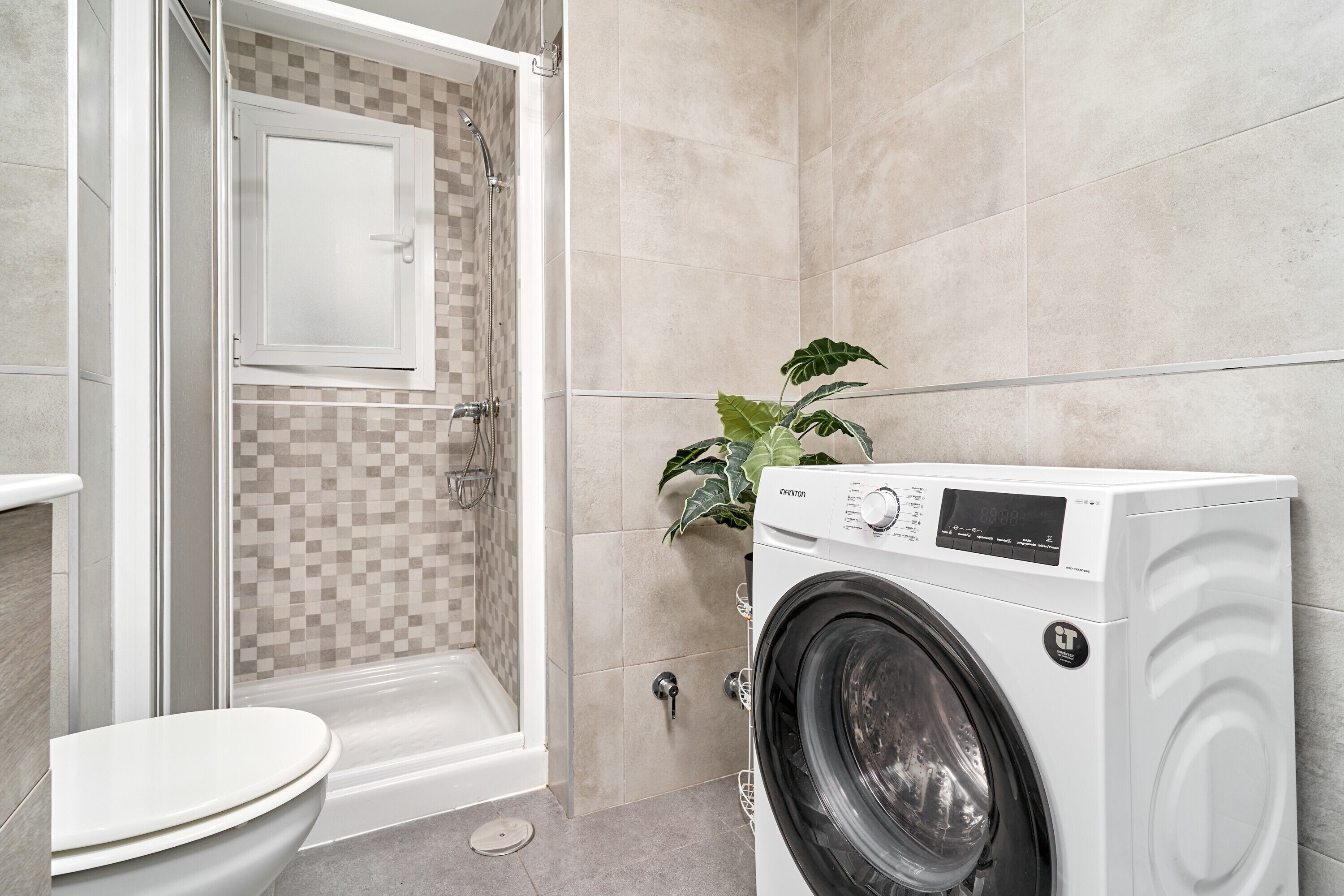 Ein Badezimmer mit Dusche, Toilette und Waschmaschine.