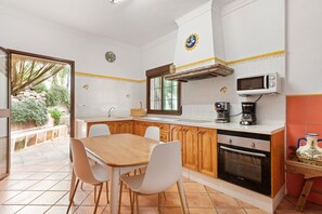 A kitchen with a dining table, chairs, a microwave, an oven, and a coffee maker. - Country House 'Casa Rural Salrima' with Mountain View, Wi-Fi and Air Conditioning (Alora)