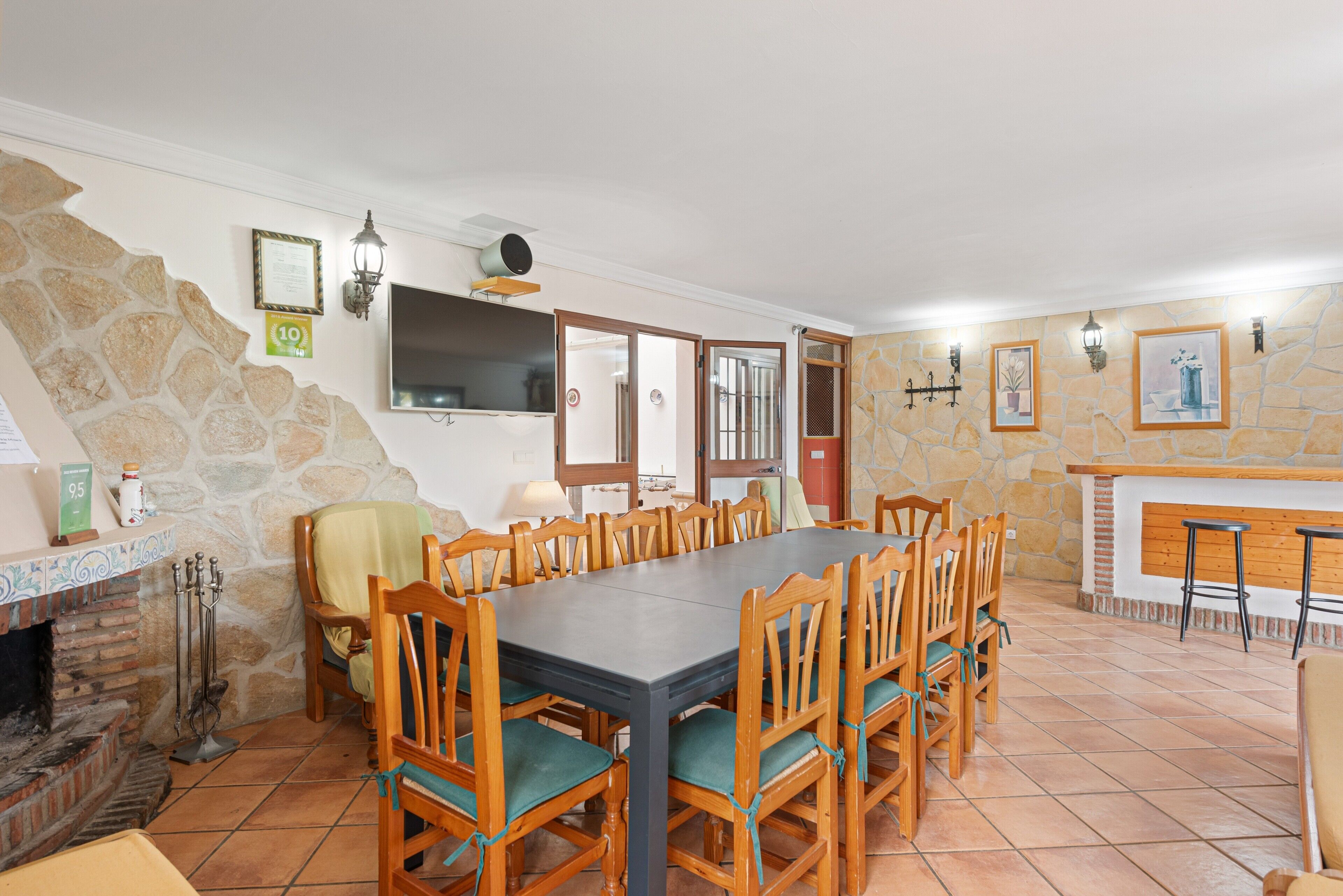 Un comedor con una mesa larga, sillas, una pared de piedra, una chimenea y una zona de bar.