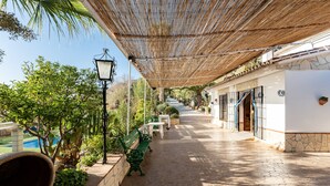 A covered outdoor area with benches, a lamp post, and a pathway leading to a building with a stone facade. - Country House 'Casa Rural Salrima' with Mountain View, Wi-Fi and Air Conditioning (Alora)
