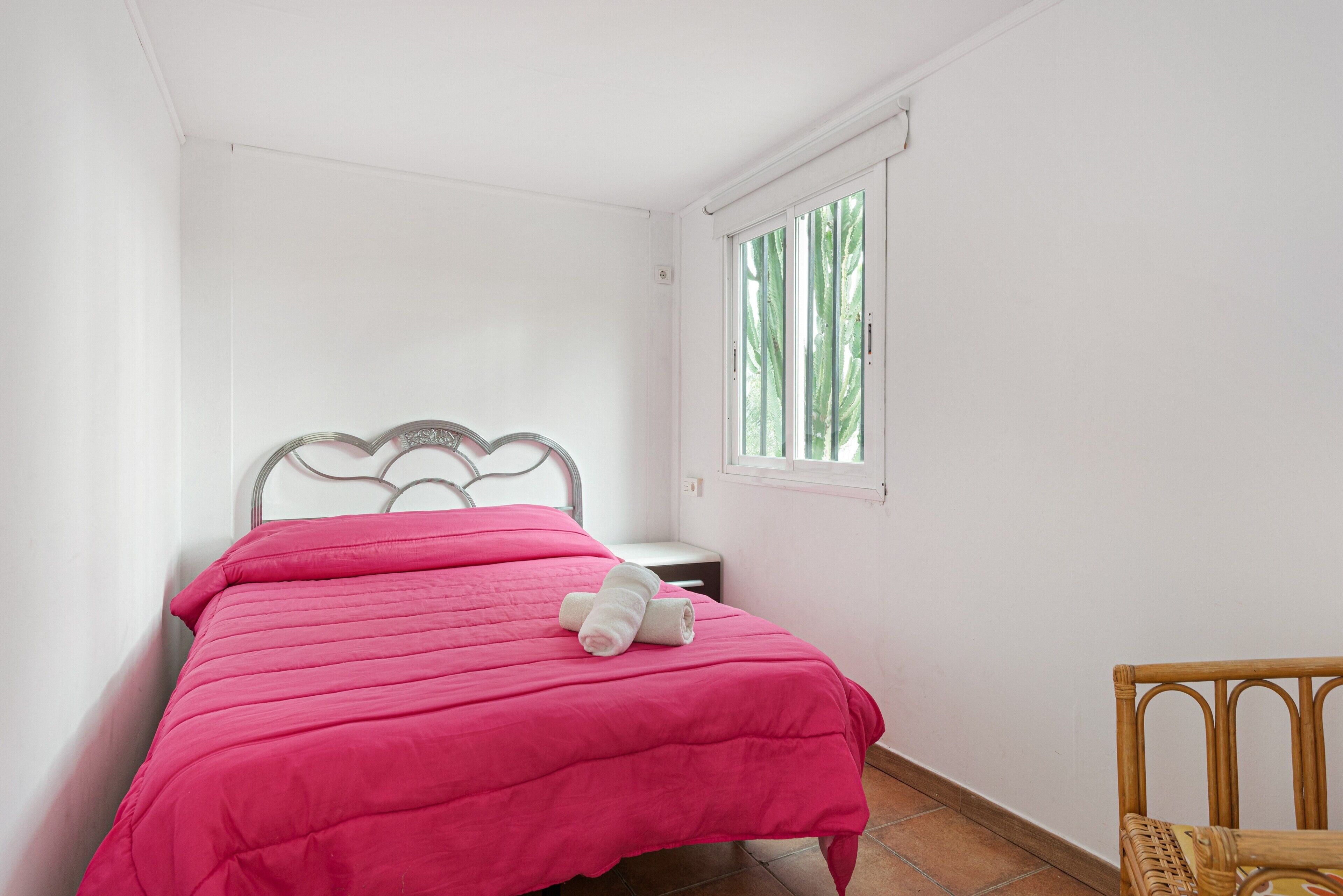 A small, neatly made room with a bed, a window, and a chair.