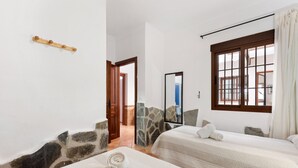 A hotel room with two beds, a stone wall, a wooden door, and a window with a view. - Country House 'Casa Rural Salrima' with Mountain View, Wi-Fi and Air Conditioning (Alora)