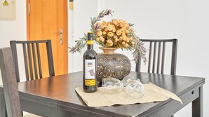 A dining table with a bottle of Shiraz wine, a vase with dried flowers, and two empty wine glasses on a placemat. - Apartment 'Balcon De Nerja' with Sea View, Wi-Fi and Air Conditioning (Nerja)