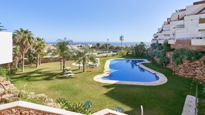 A residential area with a swimming pool, palm trees, and a view of the sea. - Apartment 'Balcon De Nerja' with Sea View, Wi-Fi and Air Conditioning (Nerja)