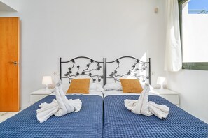 Un lit double avec une literie bleue, deux oreillers blancs et une tête de lit décorative en métal.
