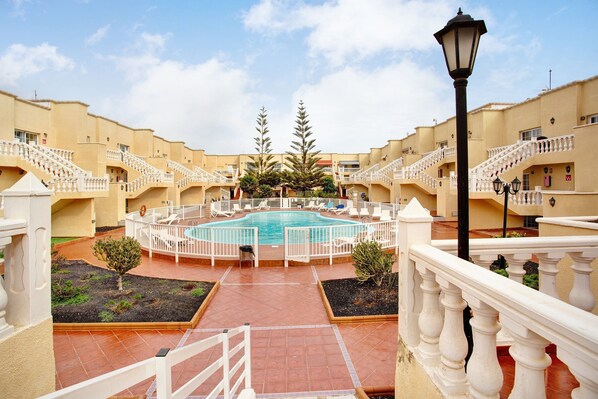 Un patio con piscina, barandas blancas y un farol.