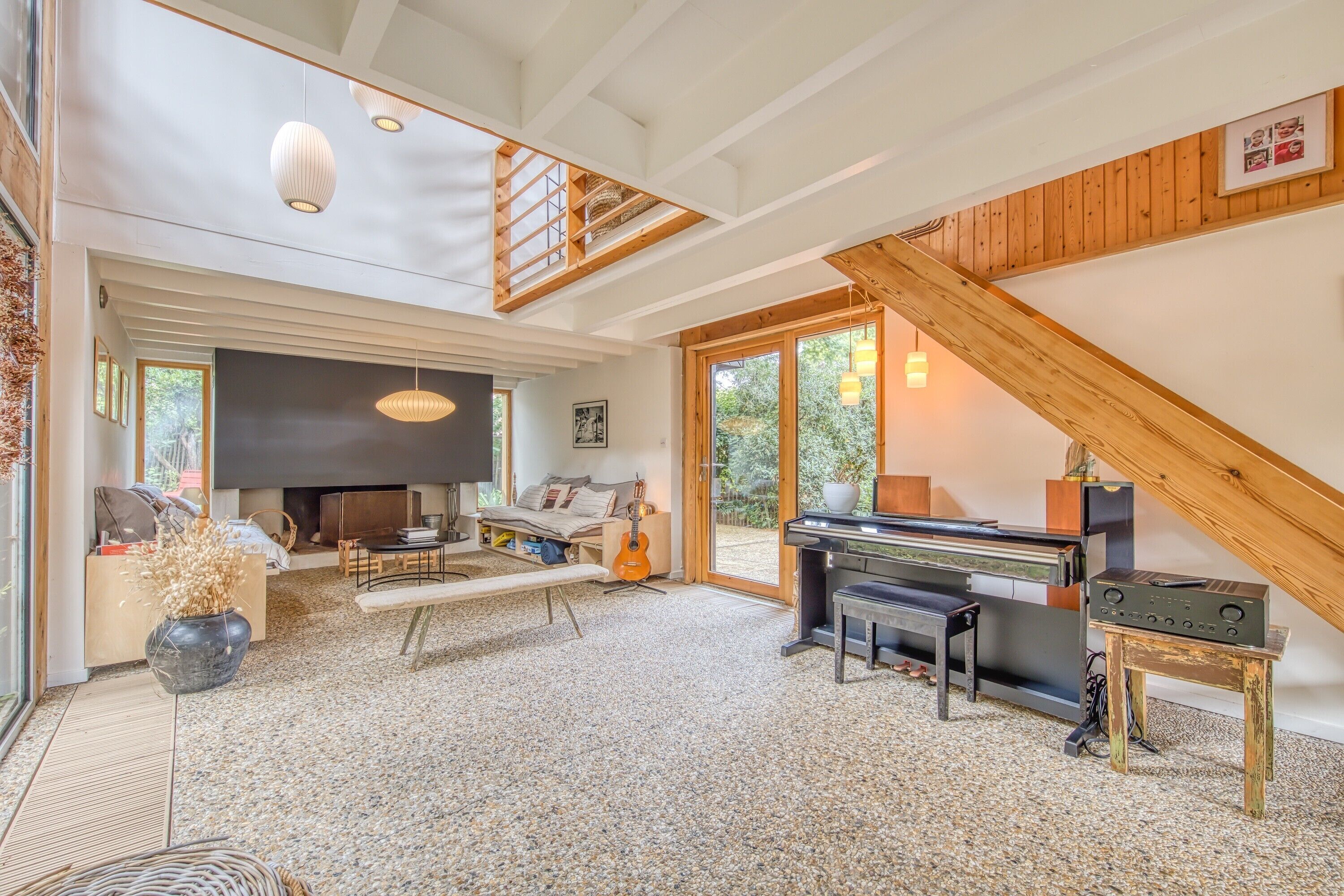 A spacious living room with a piano, a fireplace, and a large window.