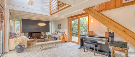 A spacious living room with a piano, a fireplace, and a large window.
