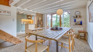 Ein Essbereich mit Holztisch und Stühlen, einer Pendelleuchte und Blick ins Freie.