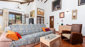Una sala de estar con un sofá estampado, una mesa de centro de madera, un sillón marrón y una mesa de comedor.