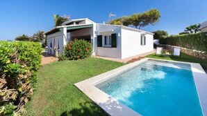 Une propriété résidentielle dotée d’une piscine, d’un patio couvert et d’une pelouse bien entretenue.