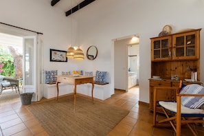 Una cocina con un armario de madera, una mesa de comedor con sillas, una lámpara colgante y vistas al exterior.