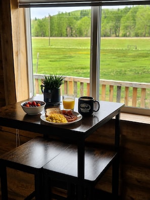 Et morgenbord med en skål frugt, ristet brød, røræg, bacon, en kop og et glas appelsinjuice.