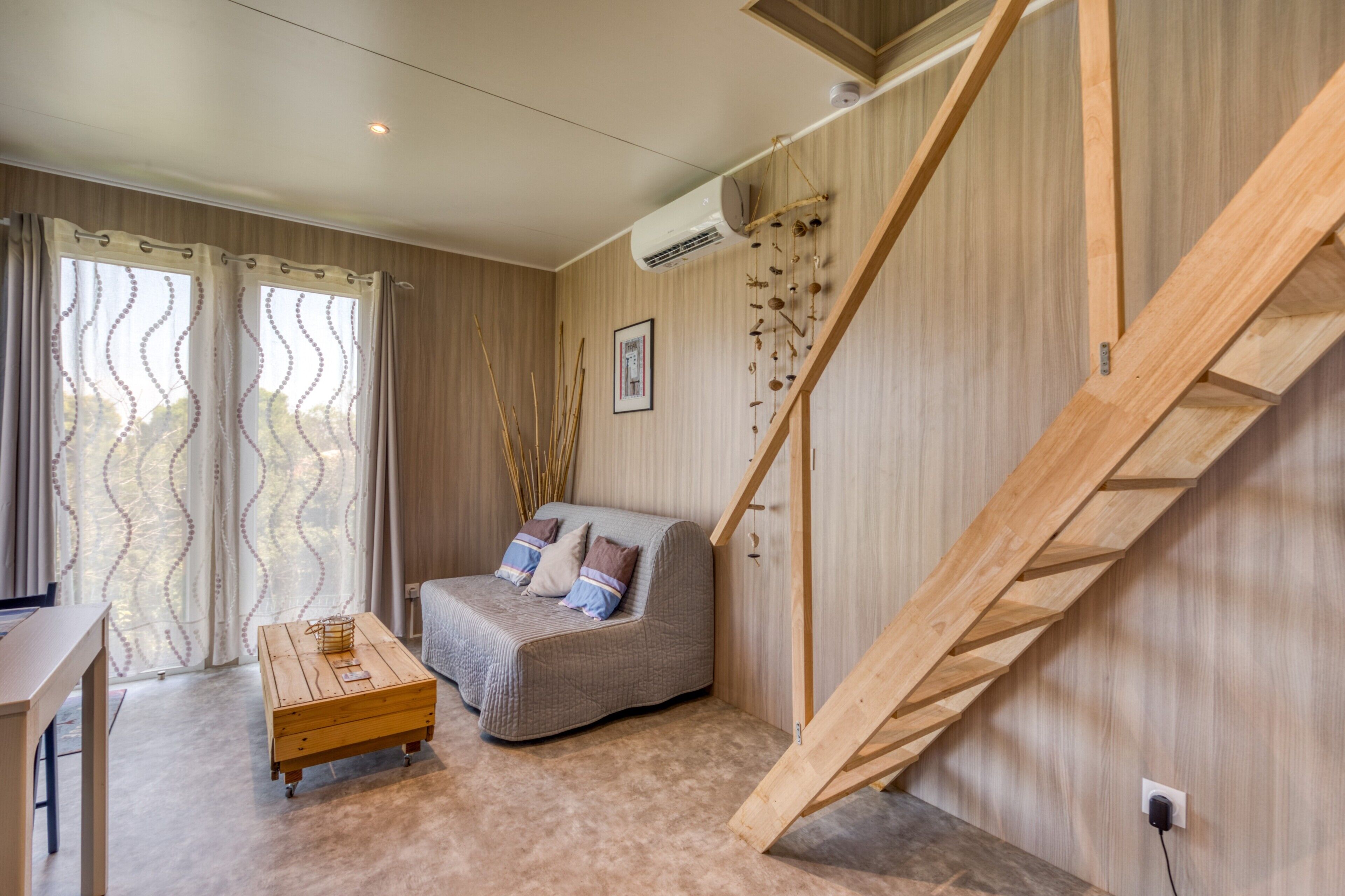 Une pièce avec un escalier en bois, un canapé, une table basse en bois et un bureau.
