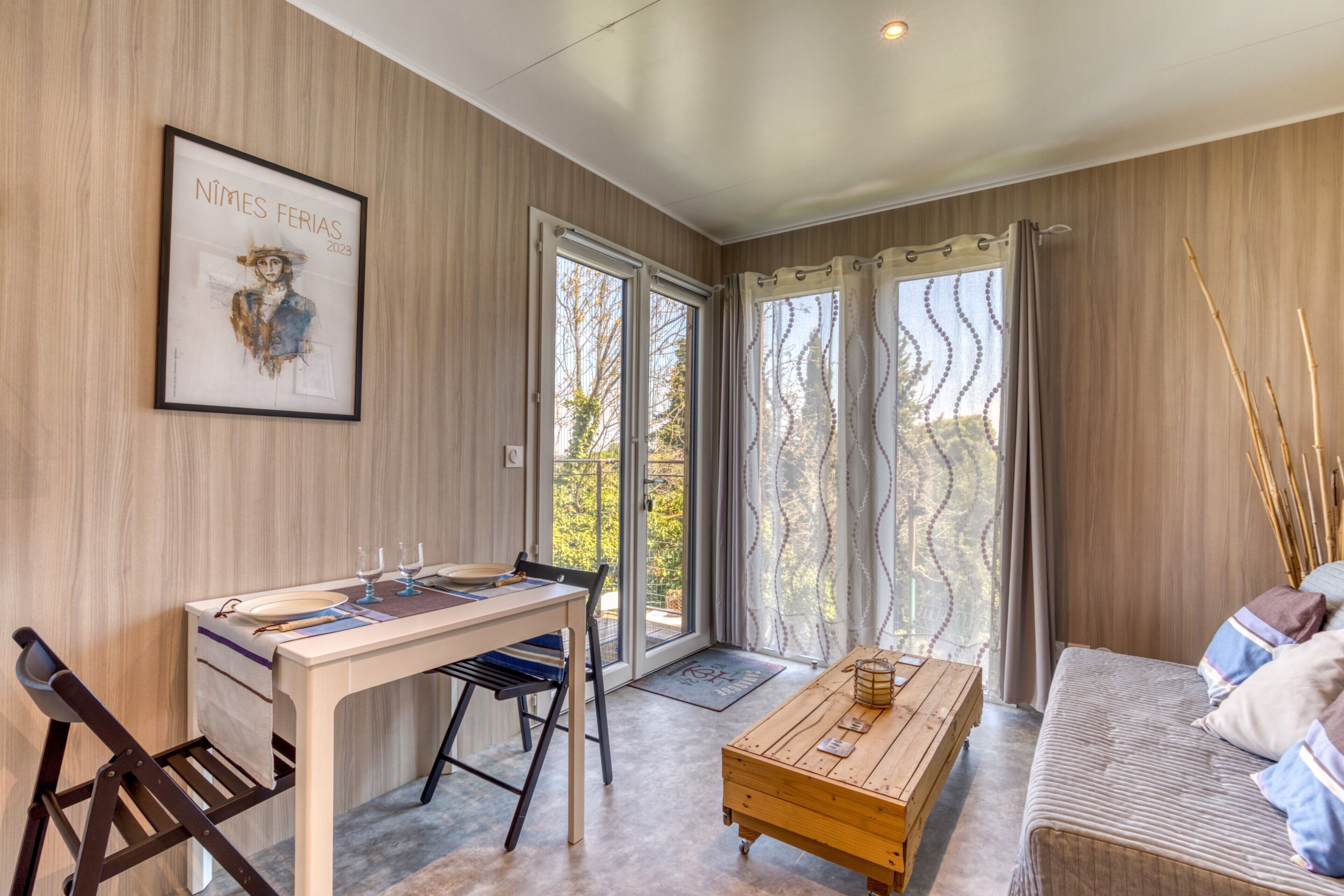 Una habitación con una mesa de comedor, sillas, un sofá, una mesa de centro y una obra de arte enmarcada en la pared.