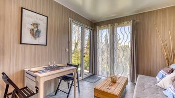 Una habitación con una mesa de comedor, sillas, un sofá, una mesa de centro y una obra de arte enmarcada en la pared.