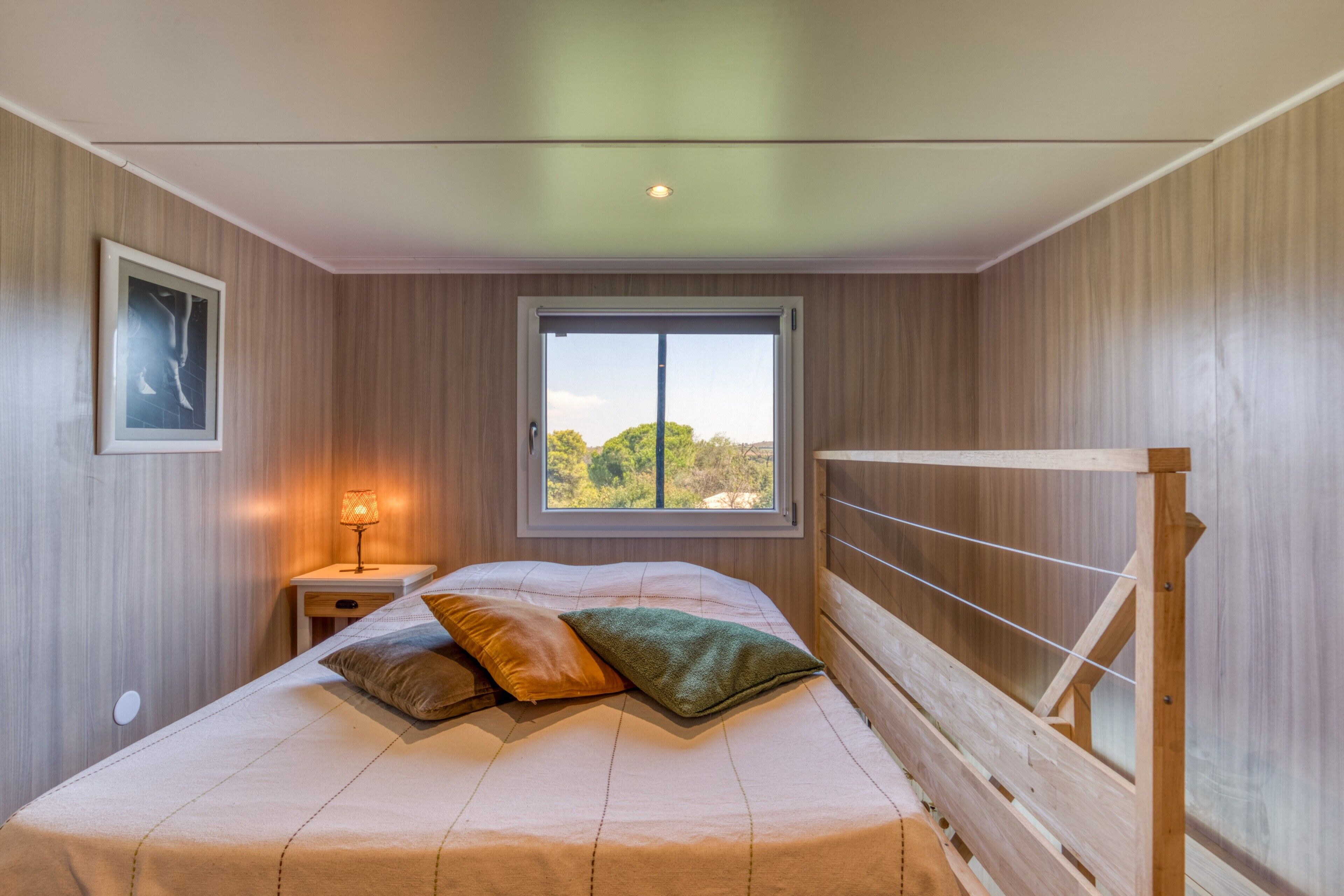 A bedroom with a bed, a window, a nightstand, and a lamp.