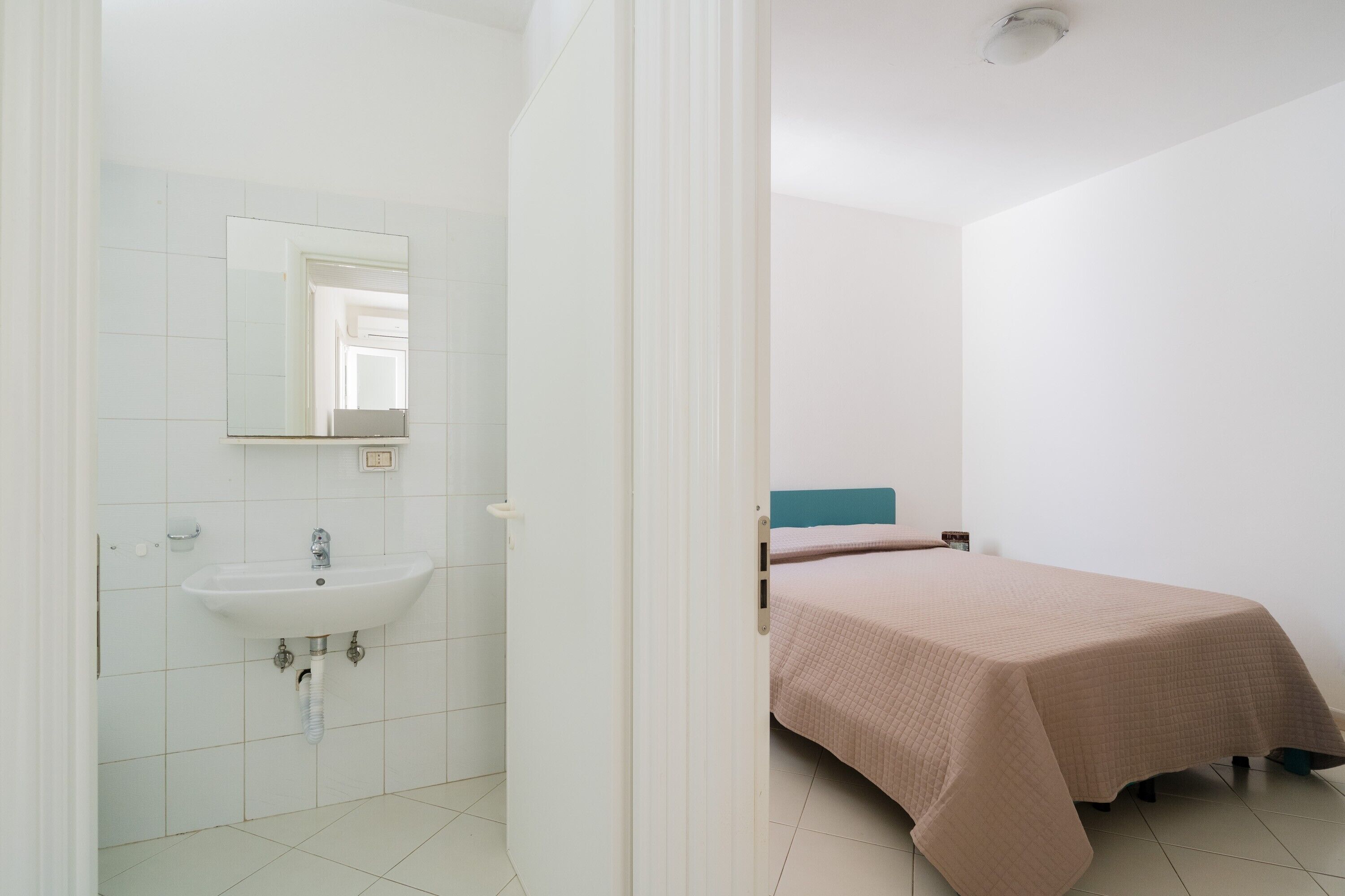 Un dormitorio con cama, mesita de noche y ventana.