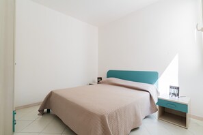 A bedroom with a bed, a nightstand, and a window.