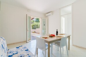 En matplats med ett bord dukat för två personer, en soffa och en skjutdörr i glas som leder ut till ett utomhusområde.