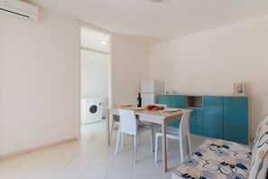 A compact living space with a kitchenette, a dining area, and a sofa.