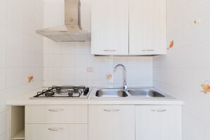 A kitchen with white cabinets, a stainless steel sink, and a gas stove.