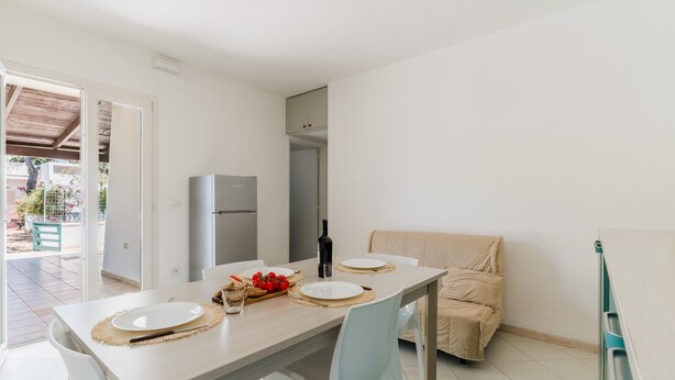Un comedor con una mesa dispuesta para dos personas, un sofá y un refrigerador.