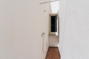 A narrow hallway with a window, a shower, and a door.