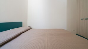 Una habitación con una cama, cabecera color aguamarina y un armario de dos puertas.